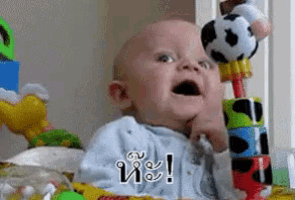 a baby is playing with a soccer ball while holding a stack of blocks with a soccer ball on top of them