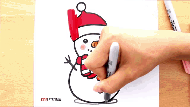 a person is drawing a snowman wearing a santa hat and scarf with a marker