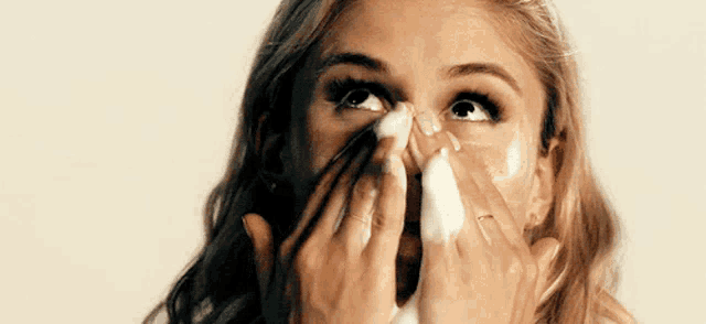 a woman is cleaning her face with foam and soap