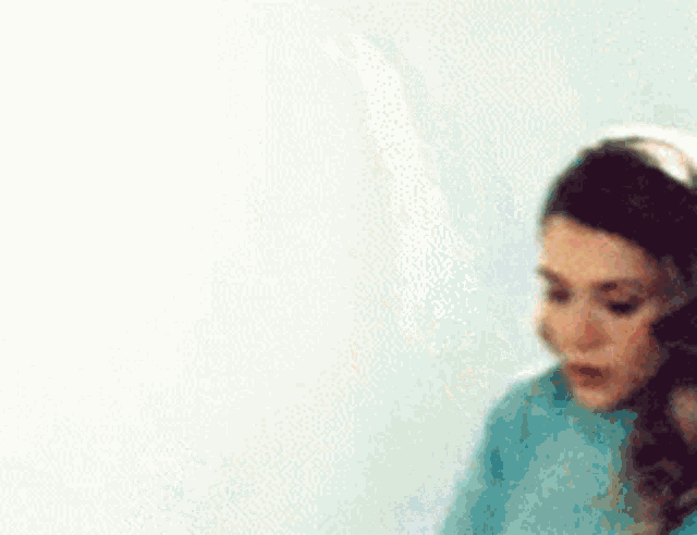 a woman in a blue sweater is wearing headphones and looking down .