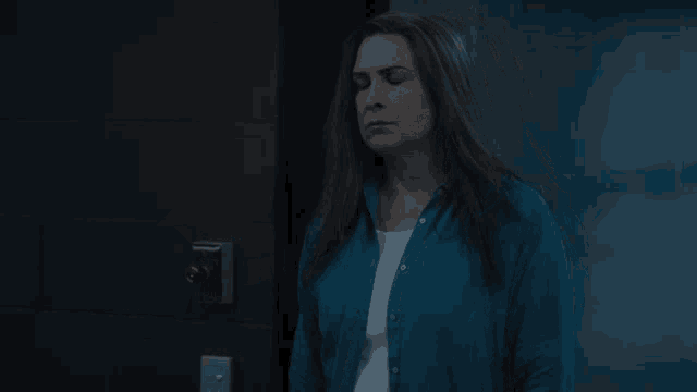 a woman in a blue cardigan stands in front of a door