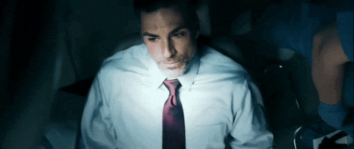 a man in a white shirt and burgundy tie is looking at something