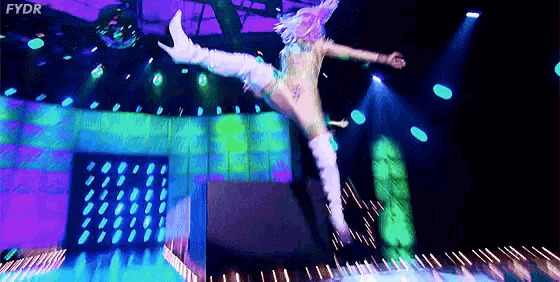 a woman is jumping in the air on a stage while wearing a costume .