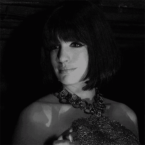 a black and white photo of a woman wearing a necklace and a dress