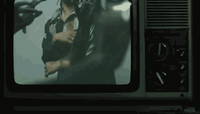a tv screen shows a man in a black jacket with a green stripe on the sleeve .