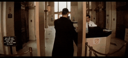 a man in a black coat is standing in front of a counter with a sign that says no smoking on it