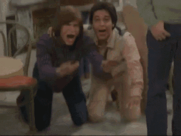a couple of boys sitting on the floor with their hands up
