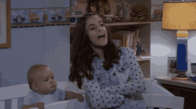 a woman standing next to a baby in a crib