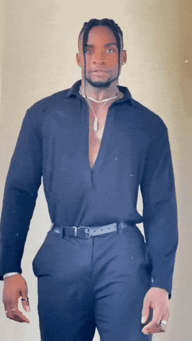 a man wearing a black shirt and black pants is standing in front of a white wall