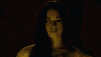 a silhouette of a person in a dark room with a yellow light behind them