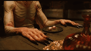 a man with bloody hands is sitting at a table with a plate of food