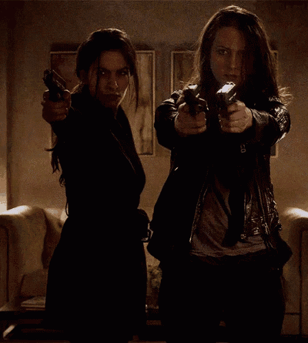 two women pointing guns at each other in a living room