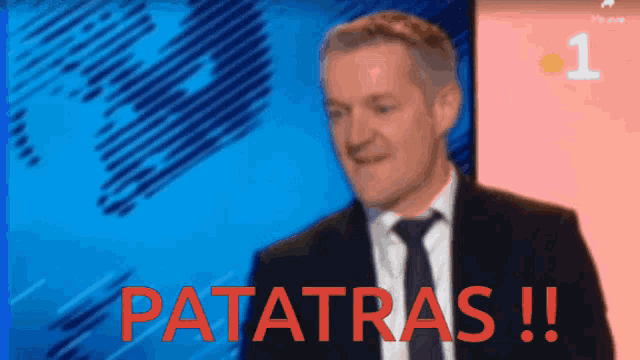 a man in a suit and tie stands in front of a screen that says patatras !!!