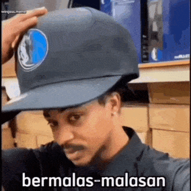 a man wearing a baseball cap with the word bermalas-malasan on it .