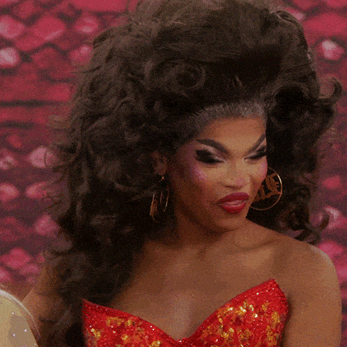 a woman wearing a red dress and gold hoop earrings with the word vogue on her lip
