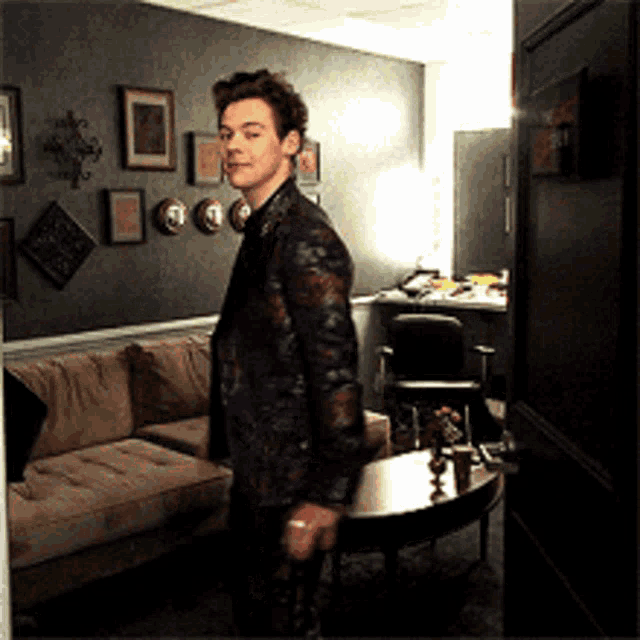 a man in a suit is standing in a room with a couch and a table