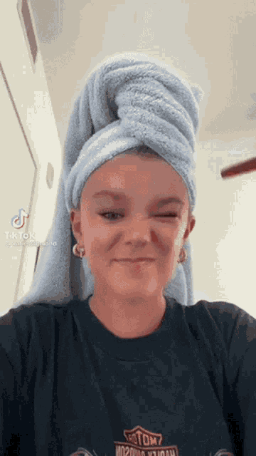 a woman with a towel wrapped around her head and a harley davidson shirt