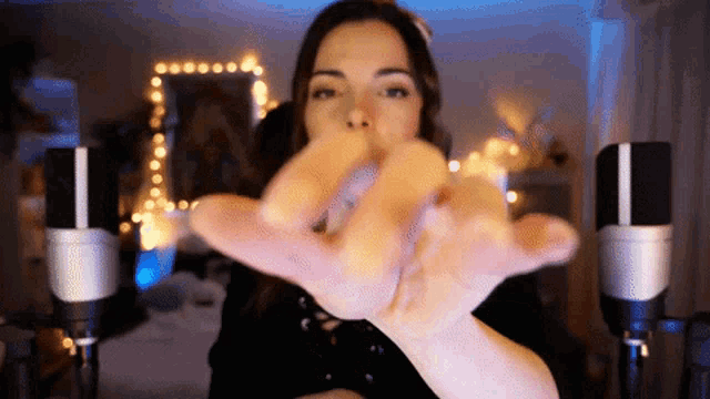 a woman is making a gesture with her hands in front of a microphone