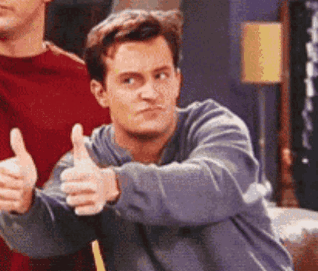 a man is giving a thumbs up sign next to another man .