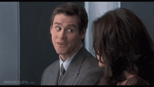 a man in a suit and tie is talking to a woman who is wearing glasses .