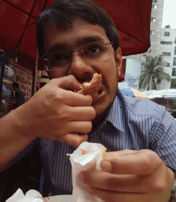 a man eating a doughnut with a sign in the background that says " fresco "