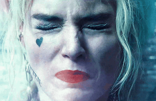 a close up of a woman 's face with a tattoo of a heart on her forehead