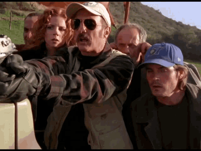 a group of people are standing around a car and one of them is wearing a new era cap