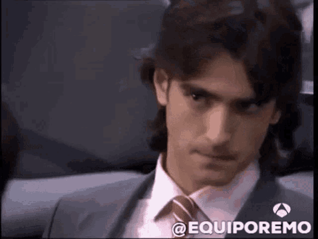 a man in a suit and tie is sitting in a chair with the word equiporemo on the bottom right