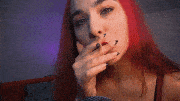 a woman with red hair smoking a cigarette with her eyes closed