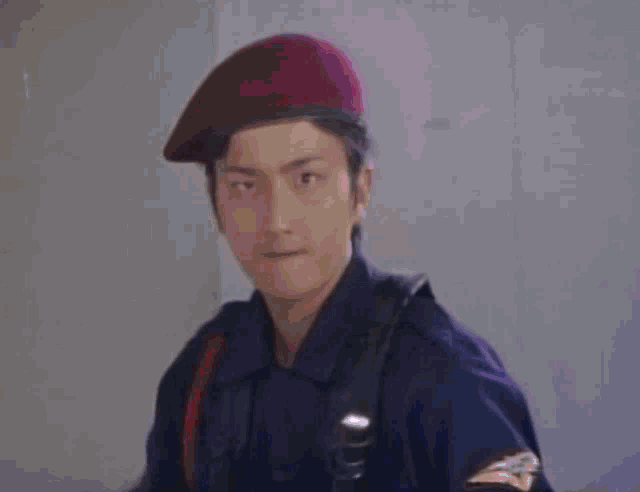 a man in a military uniform is wearing a red beret and holding a baton .