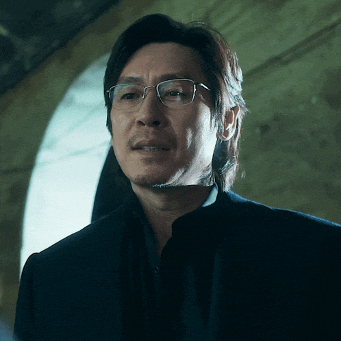 a man wearing glasses and a black shirt looks at the camera