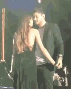 a man and woman are dancing on a stage and the woman is wearing a black dress
