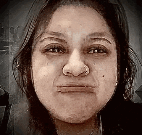 a woman with a nose ring is making a funny face with her eyes closed .