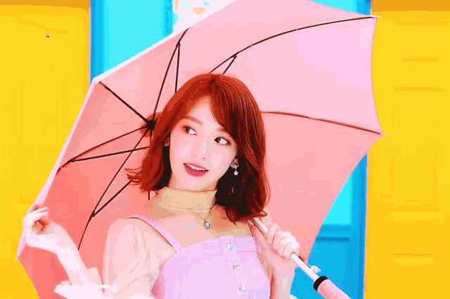 a woman is holding a pink umbrella in front of a yellow wall