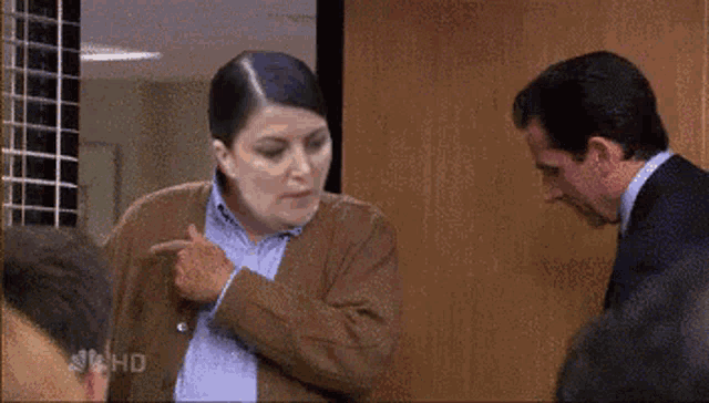 a man and a woman are standing next to each other and the woman is pointing at the man 's chest