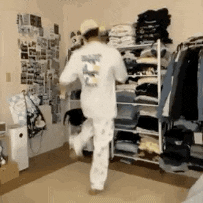 a man in pajamas is dancing in a room with a closet filled with clothes .