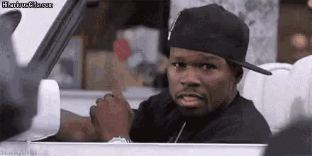 50 cent is sitting in the driver 's seat of a car giving the middle finger .
