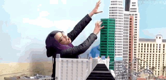 a woman is standing in front of a miniature city with her arms outstretched .