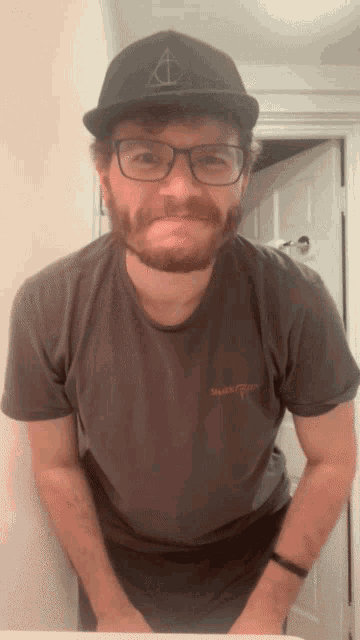 a man with a beard wearing glasses and a hat with a triangle on it