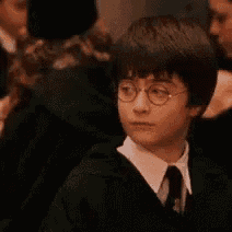 harry potter is wearing glasses and a tie while standing in a crowd .