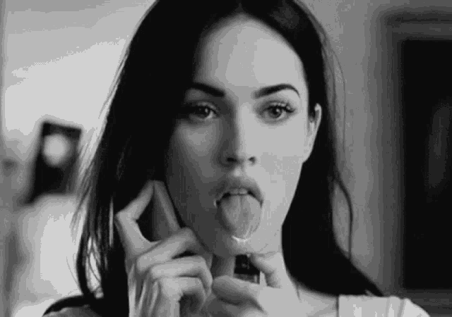 a woman is sticking her tongue out in a black and white photo .
