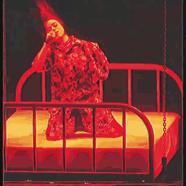 a woman in a red dress is sitting on a bed in a cage
