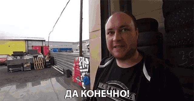 a man wearing a black shirt that says ' halt ' on it is standing in a parking lot