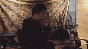 a man playing a guitar in front of a keyboard with the letter d visible