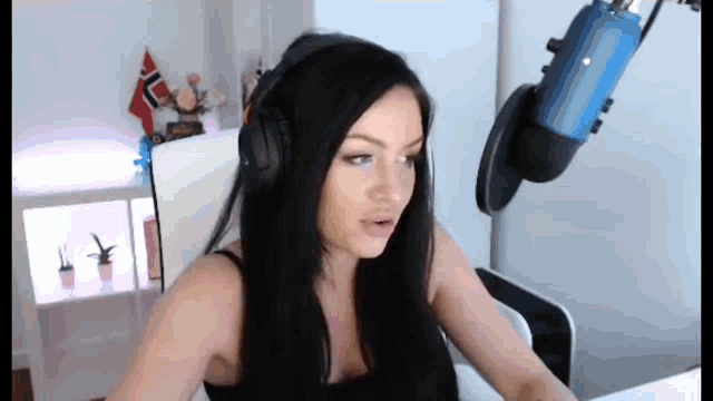 a woman wearing headphones sits in front of a microphone