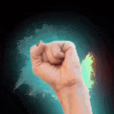 a person 's fist is raised in the air in front of a blue and green background