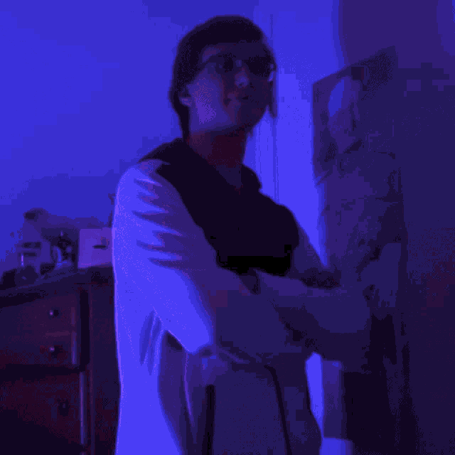 a man wearing glasses is standing in front of a purple light