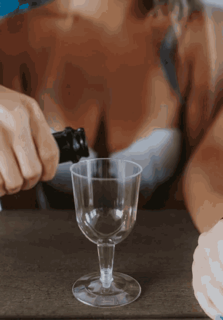 a person pouring wine into a small glass
