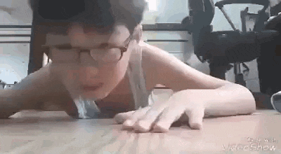a young boy wearing glasses is laying on the floor .