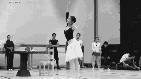 a black and white photo of a ballerina in a tutu performing a dance on a stage .